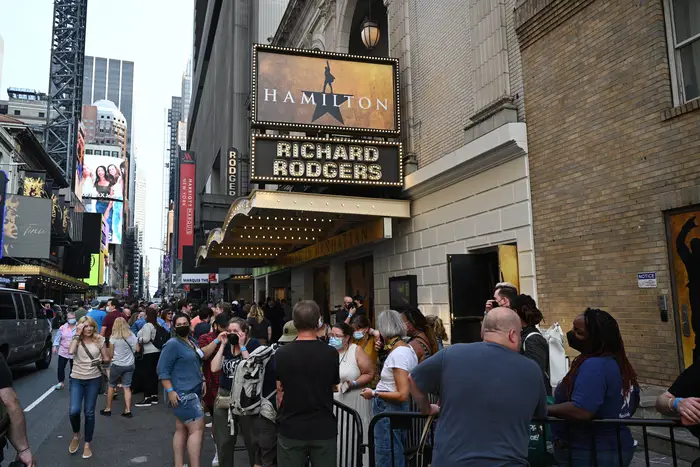 The marquee of Hamilton can be seen over the crowd of theatergoers